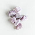 A bunch of soft purple, rough Kunzite stones on a white background.