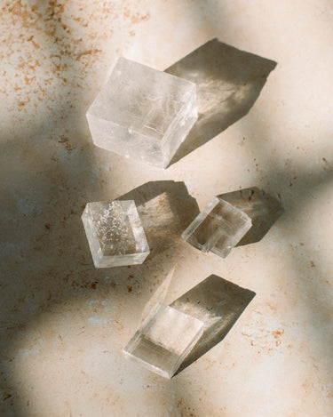 Photo of four pieces of optical calcite on a sandstone background.