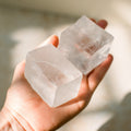 Hand holding two pieces of optical calcite.